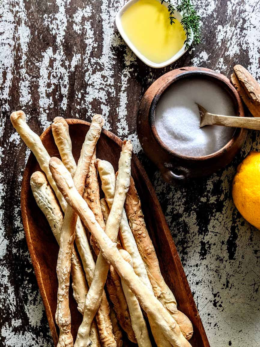 Italienische Grissini mit Olivenöl, Salz und Zitrone auf rustikalem Holztisch