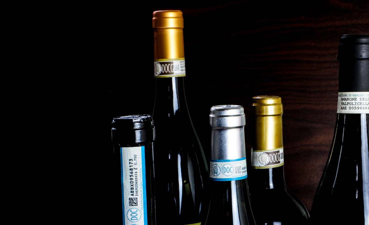 Fünf edle italienische DOC und DOCG Weinflaschen mit hochwertigen Etiketten vor dunklem Hintergrund