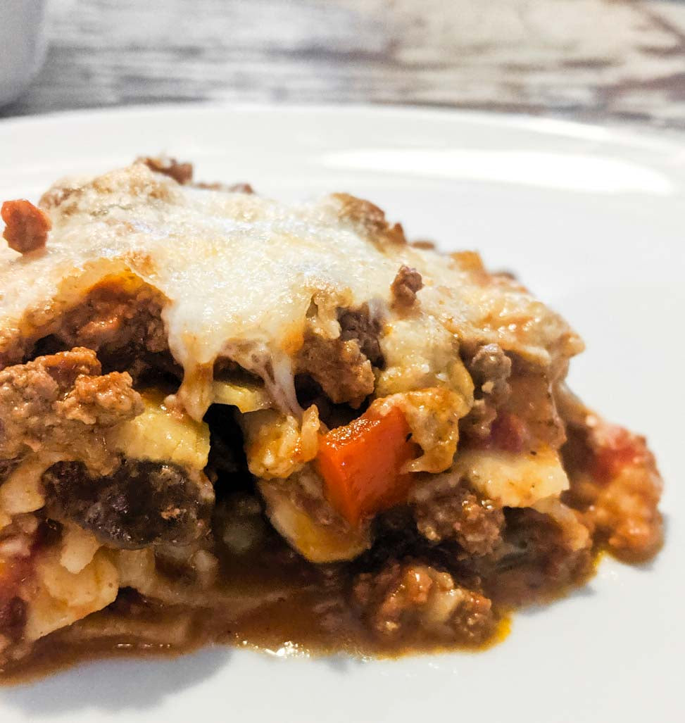 Hausgemachte Lasagne mit geschmolzenem Käse, Hackfleisch, Tomaten und Pastaschichten auf Teller