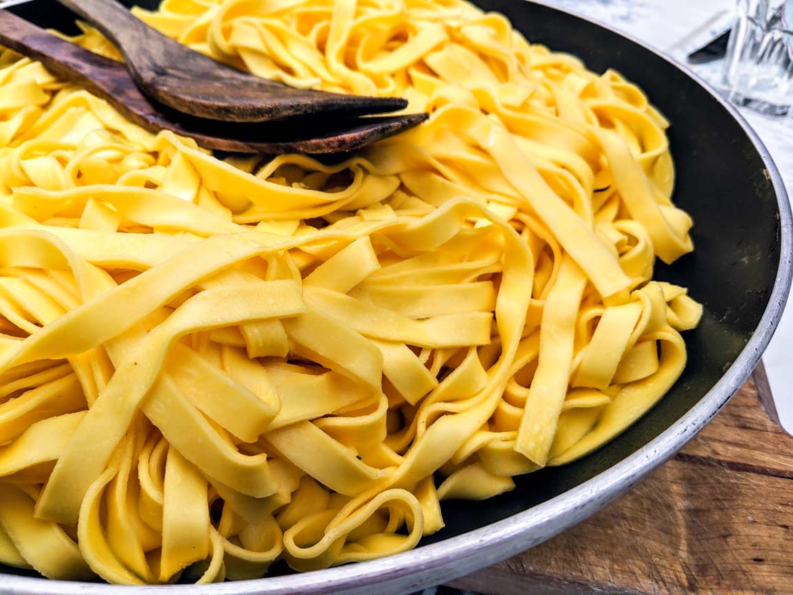 Frisch gekochte Tagliatelle Pasta in einer Pfanne mit Holzlöffeln serviert