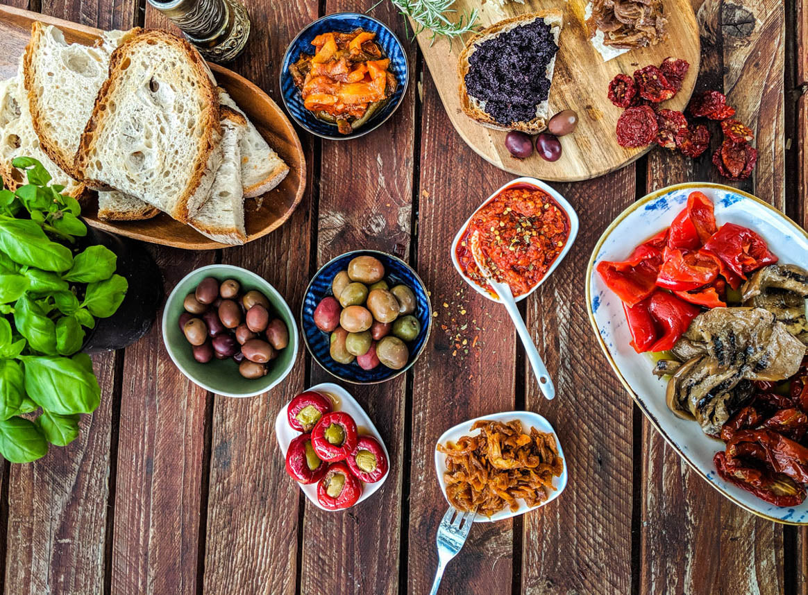 Italienische Feinkost, Olivenöl, Wein und Antipasti auf einem mediterran gedeckten Tisch