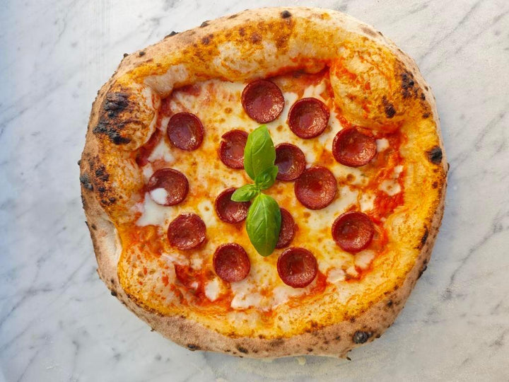 Italienische Pizza mit knusprigem Rand, Salami, Mozzarella, Tomatensauce und Basilikum