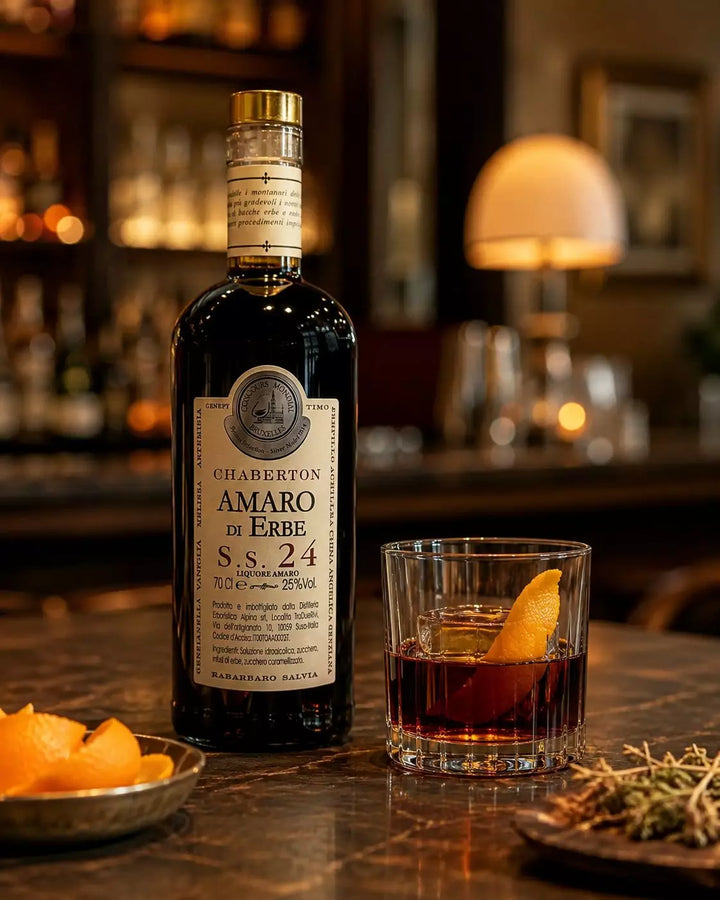 Chaberton Amaro di Erbe S.S. 24 mit Servierglas, Eiswürfel und Orangenzeste in einer stilvollen Barumgebung
