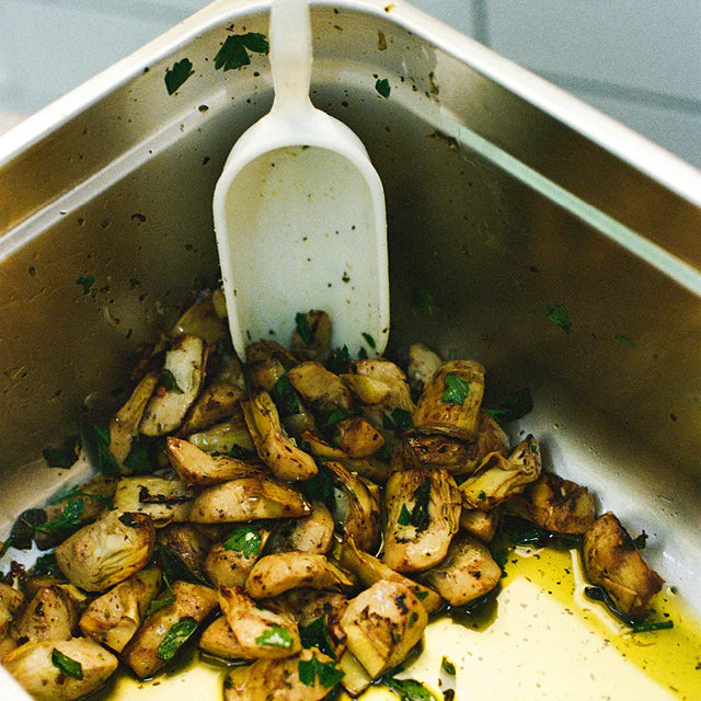 Gegrillte Artischocken in Öl mit Kräutern in Edelstahlbehälter, italienische Vorspeise