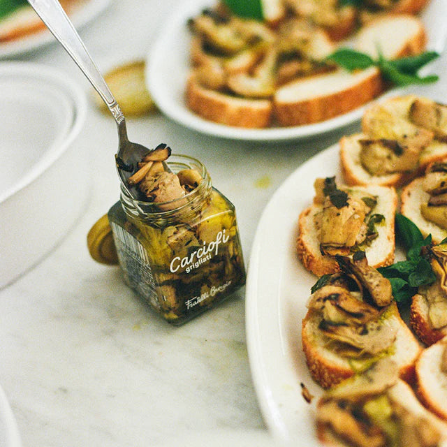 Gegrillte Artischocken Carciofi Grigliati im Glas, serviert auf geröstetem Brot mit Kräutern