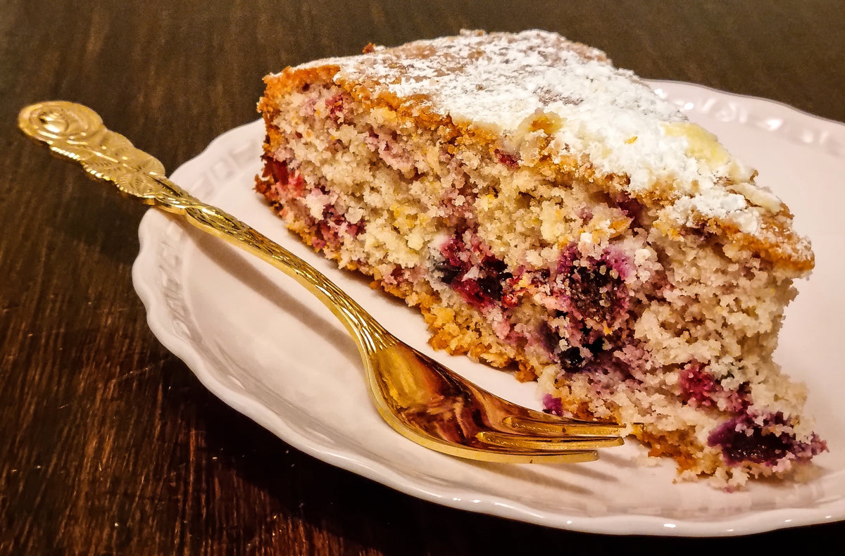 Glutenfreier Kuchen mit Reismehl und Beeren, bestäubt mit Puderzucker auf weißem Teller